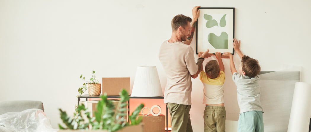 Dad and two small boys hanging a picture frame