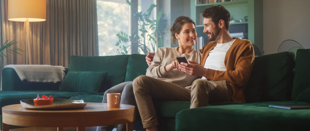 young couple sitting on a sofa and looking at a smartphone